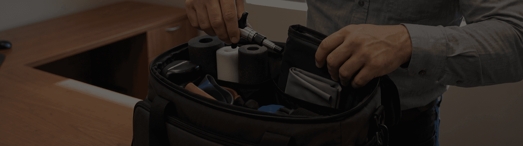 A therapist selecting massage tools from a bag of soft-tissue equipment