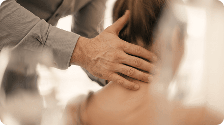 Hand assessing a patient's neck for whiplash-related disc injury